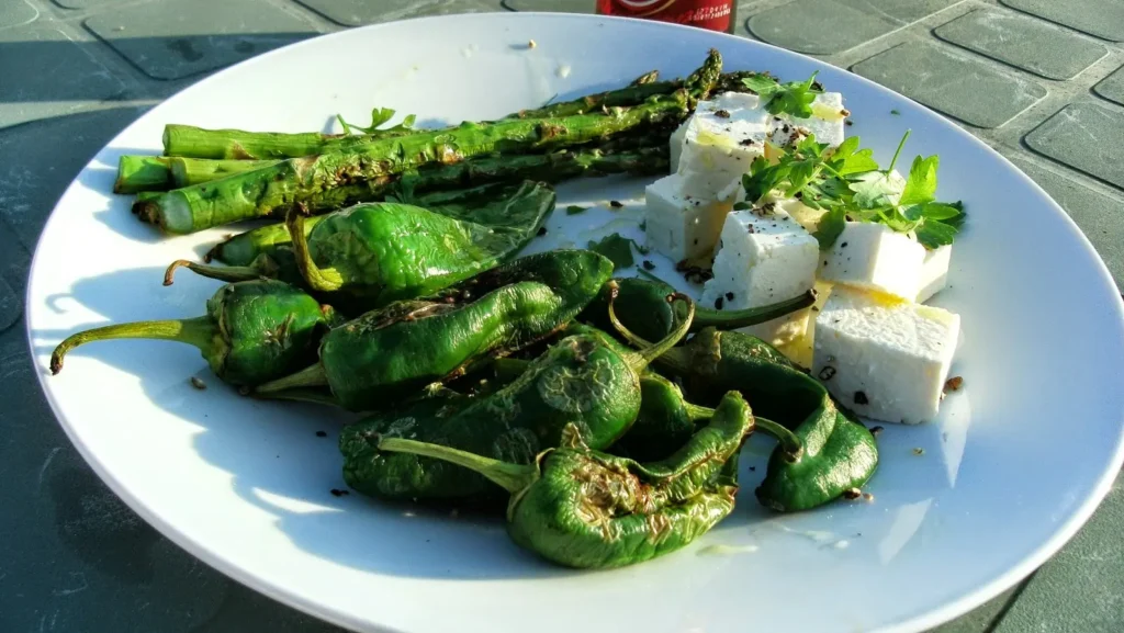 Griddled asparagus and blistered pimientos de Padrón with feta, parsley and black pepper on the roof terrace at Casa Adora