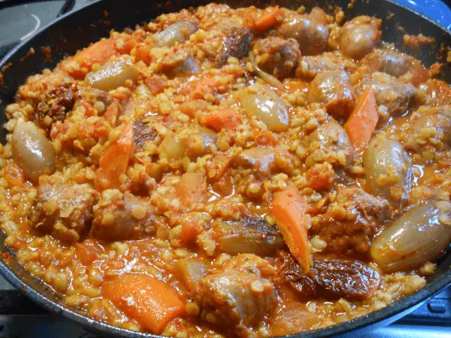 Sausage casserole with spicy tomato, pearl barley, red lentils, carrot and whole shallots in a frying pan — Casa Adora