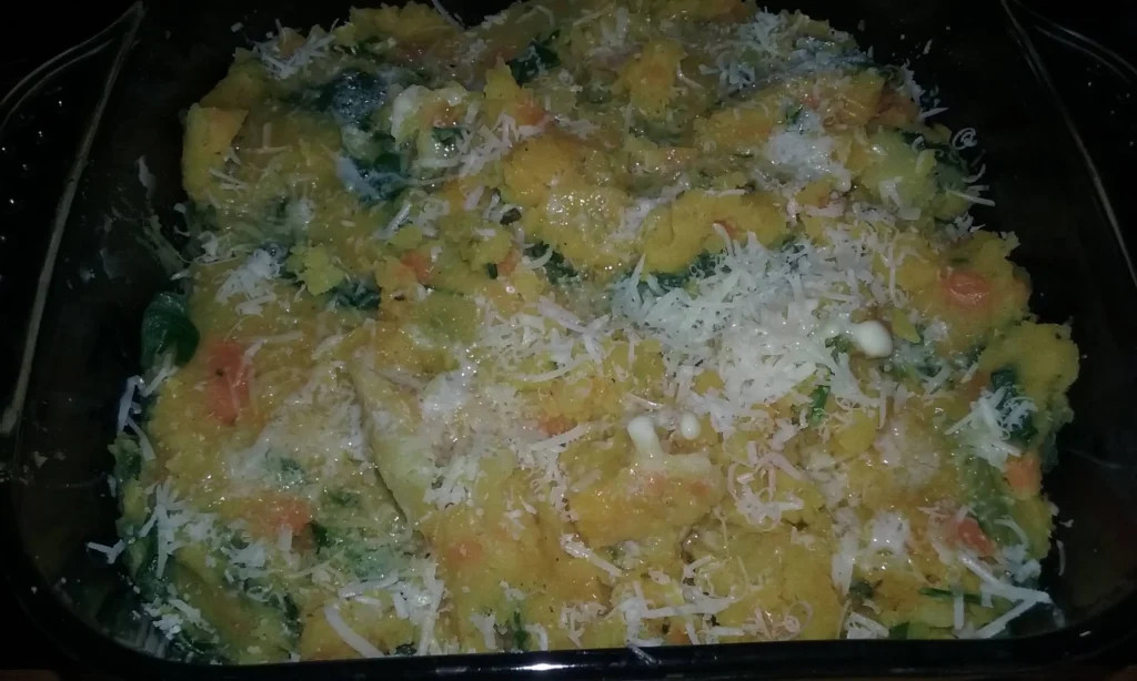 Baked sweet potato and chard bubble and squeak in a glass ovenproof dish, topped with grated parmesan, golden and crisp from the oven