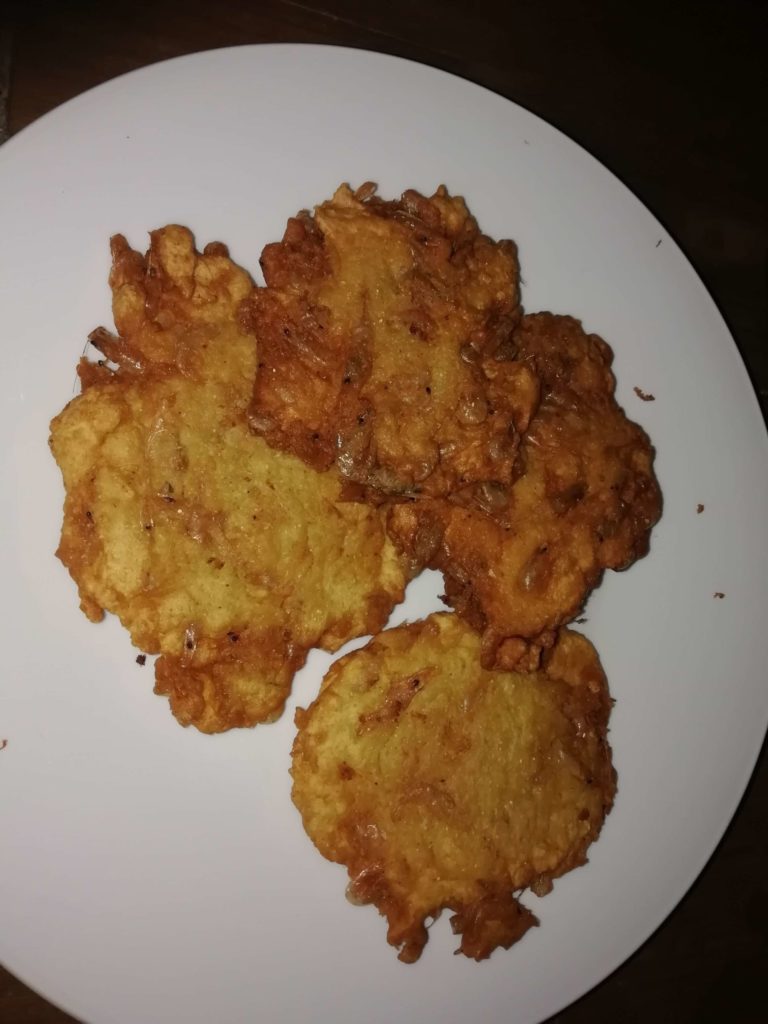 Thin, lacy Spanish shrimp fritters (Tortillitas de Camarones) served on a rustic plate with a wedge of lemon.