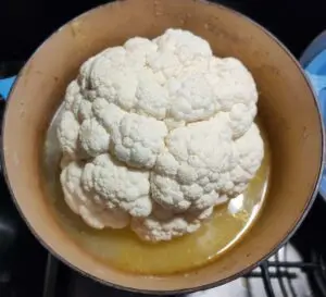 Whole cauliflower simmering in chicken stock in a Le Creuset pan – cauliflower purée recipe – The Flexible Chef