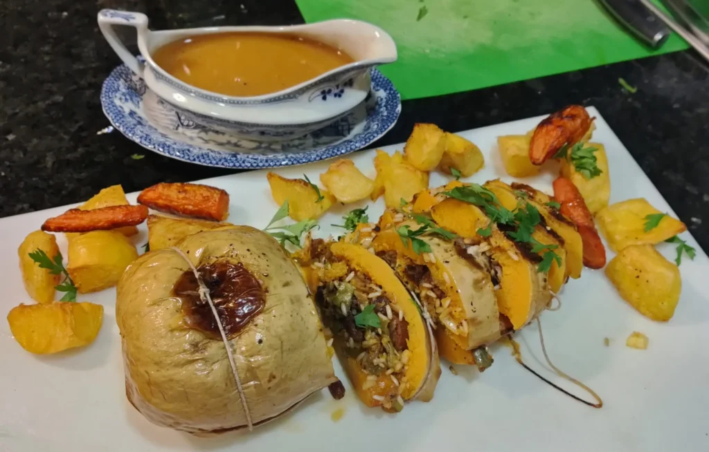 Baked stuffed butternut squash served with roast potatoes, roasted carrots, and homemade gravy in a blue and white gravy boat at Casa Adora