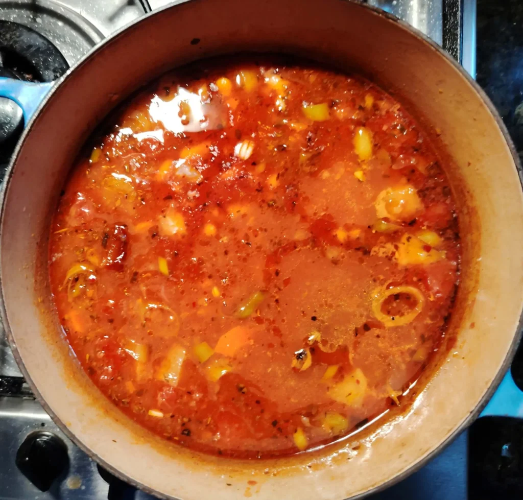 A Le Creuset pan simmering on the hob with Greek Bean Stew