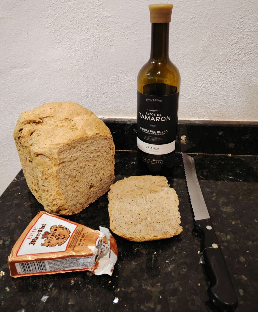 Rustic wholemeal loaf on granite worktop with a bottle and red wine and Brie cheese