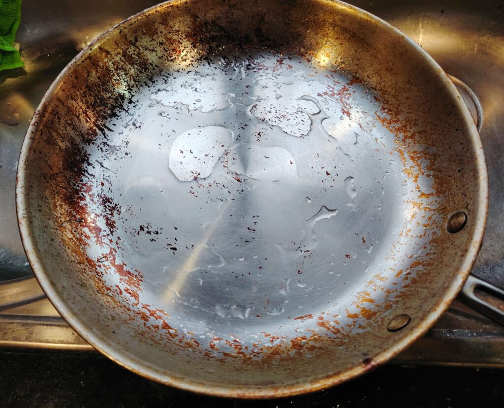 Frying pan with water droplets after cleaning with vinegar and baking soda paste.