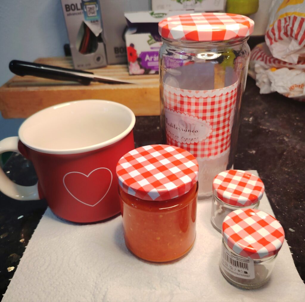 A finished bottle of Sunstrike Habanero fermented chilli sauce sitting on a paper towel next to a red heart-patterned mug.