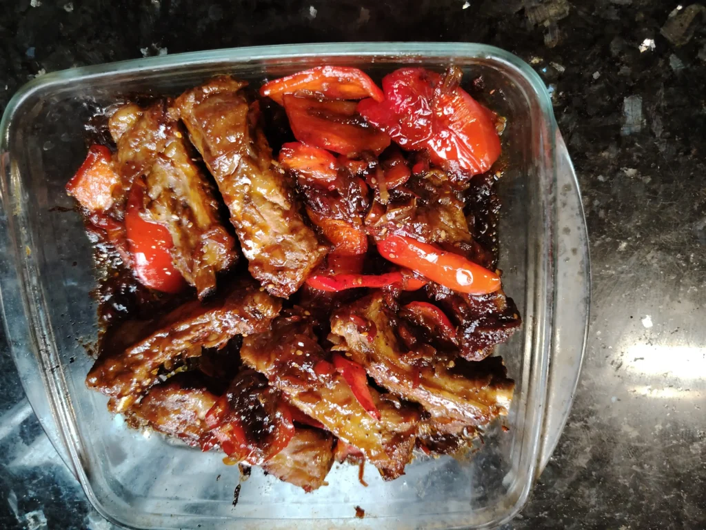 Pork ribs with Hoisin glaze and red pepper, caramelised and sticky in a glass dish at Casa Adora