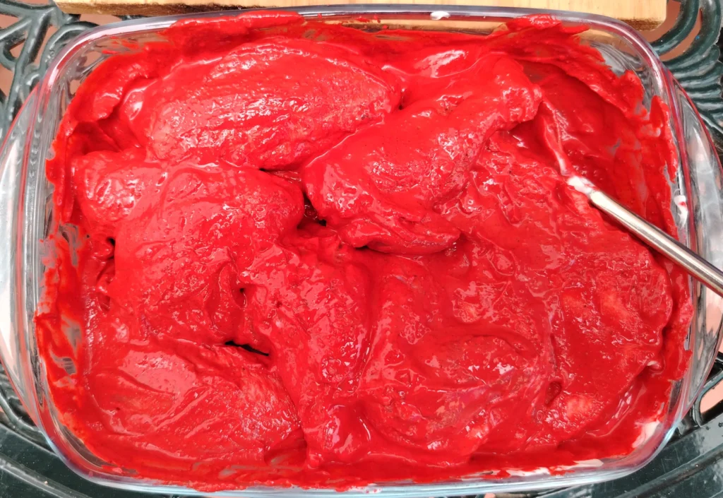 Tandoori chicken wings coated in vivid red beetroot powder marinade in a glass dish — Casa Adora