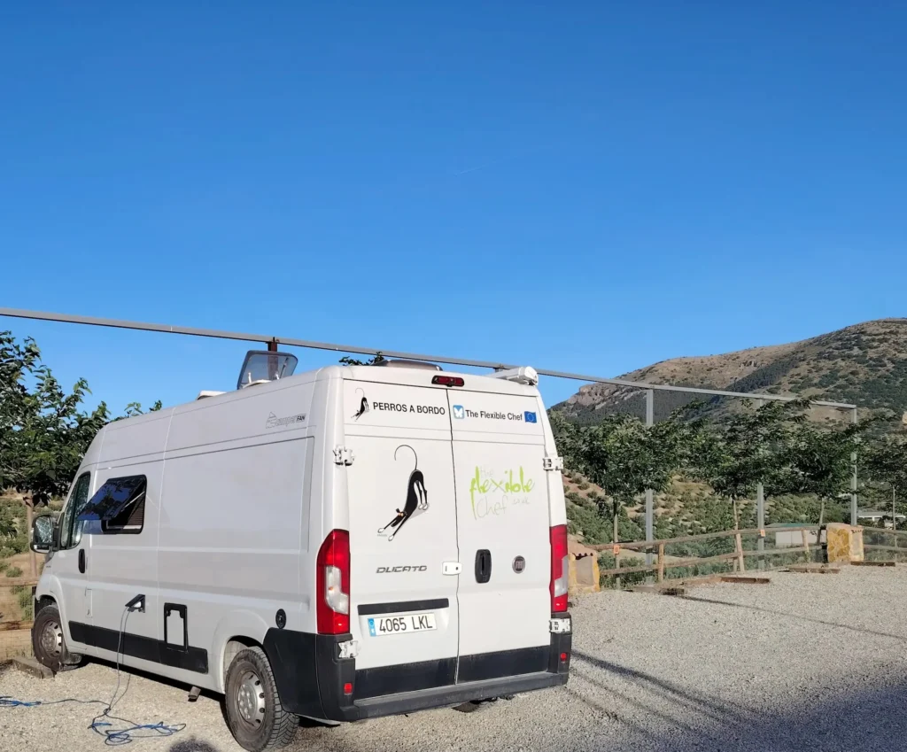 Florie the campervan parked at Complejo Rural Los Cortijos de Noalejo with Andalucían mountains behind