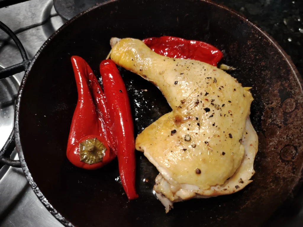 Corn-fed chicken leg and blistered red peppers in a cast iron pan β the cold pan method in action