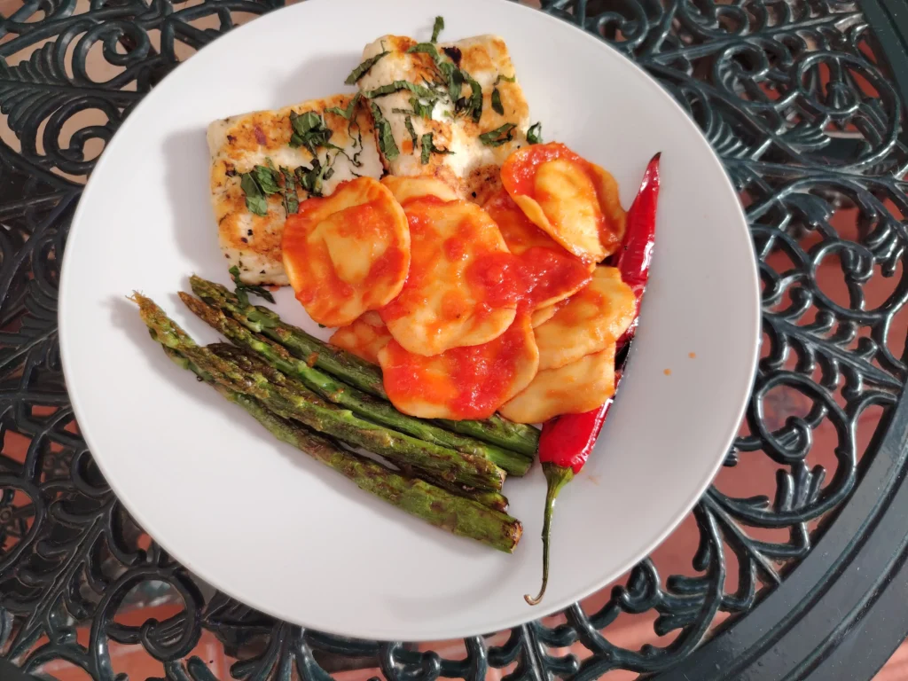 Pan-fried halloumi with mint, goat's cheese ravioli and chargrilled asparagus on a white plate