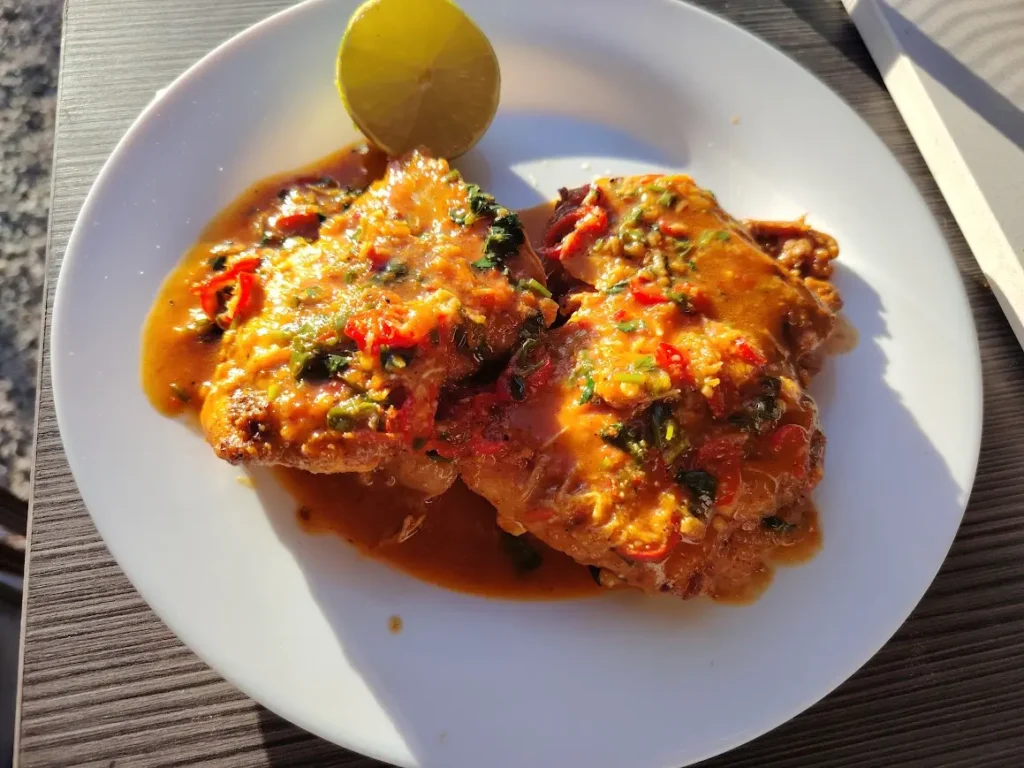 Spicy beer-braised garlic chicken thighs in a cast iron pan, cooked in a campervan kitchen