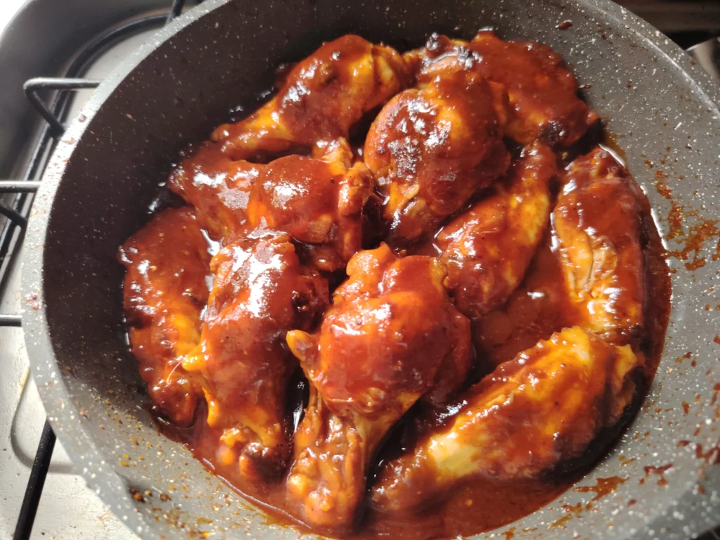 Sticky glazed chicken wings reducing in a pan on a van hob — Cruzcampo glaze, smoked pimentón