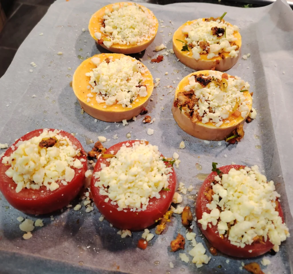 Stuffed tomato rings and butternut squash rings filled with egg and topped with grated mozzarella, ready to bake
