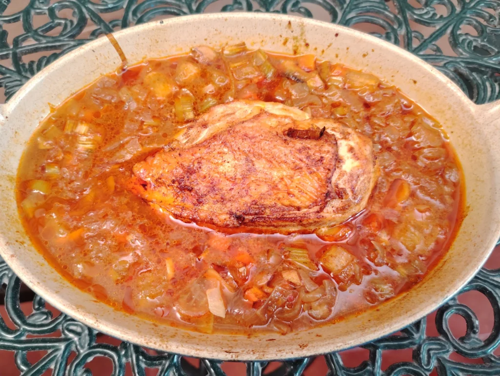 Harissa chicken recipe — a Tunisian marqa with braised chicken breast, root vegetables and harissa in a ceramic dish on a Casa Adora terracotta table