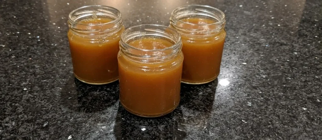 Membrillo recipe — three jars of soft-set quince paste made with rosemary honey and PX on a black granite worktop at Casa Adora