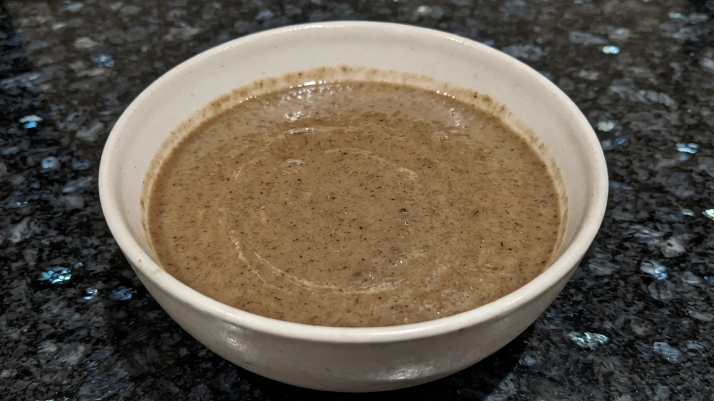 Vegan mushroom soup in a cream bowl on black granite β vegan mushroom soup recipe β The Flexible Chef